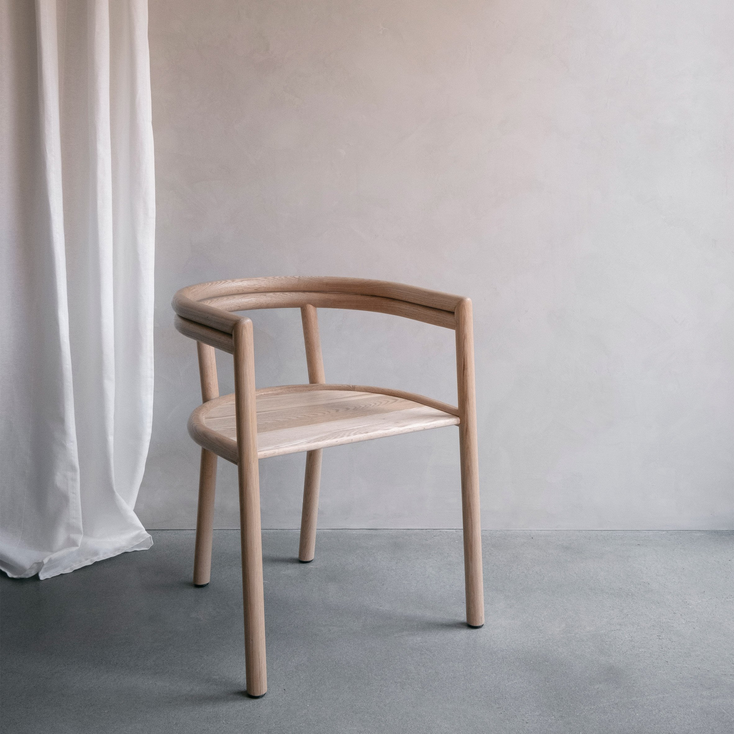 Elsie wooden chair with armrests in a neutral-toned room