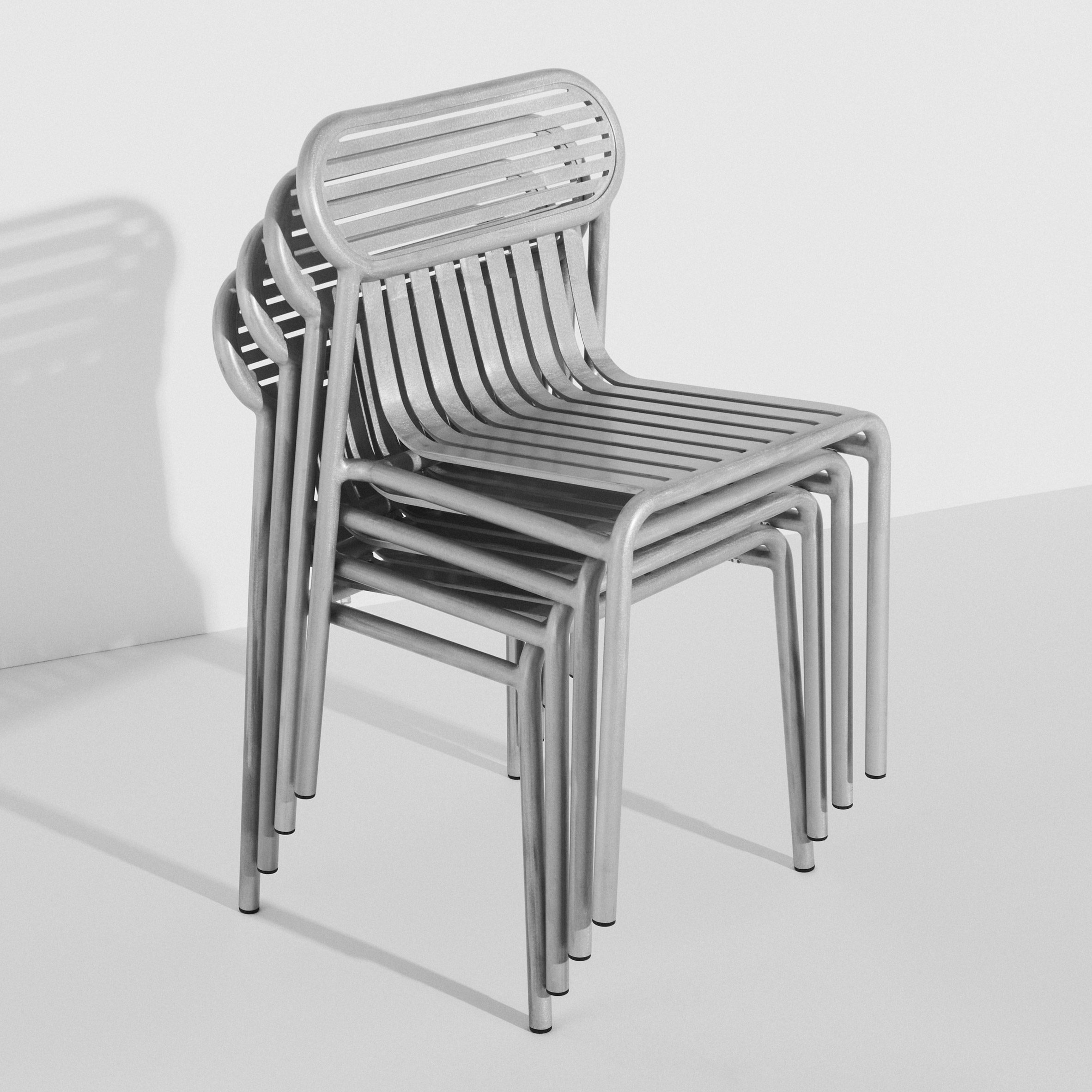 Shiny metallic chairs stacked up in white room