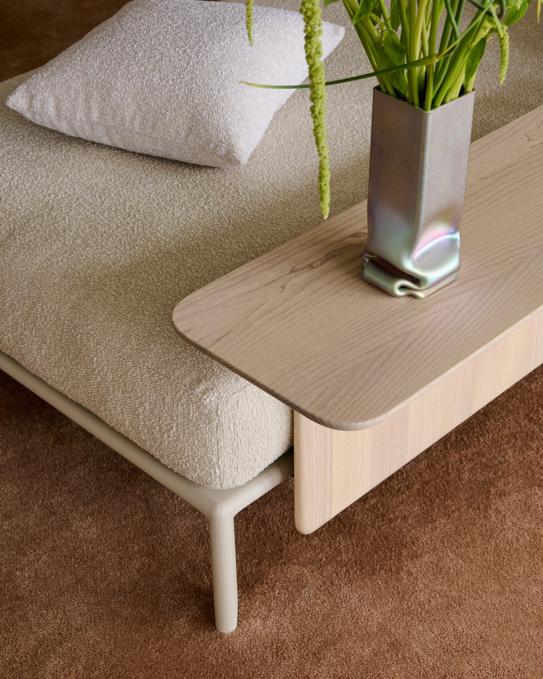 Close-up photo of a detail of the Anagram sofa in a cream-white boucle-type fabric with a side table attached to the frame