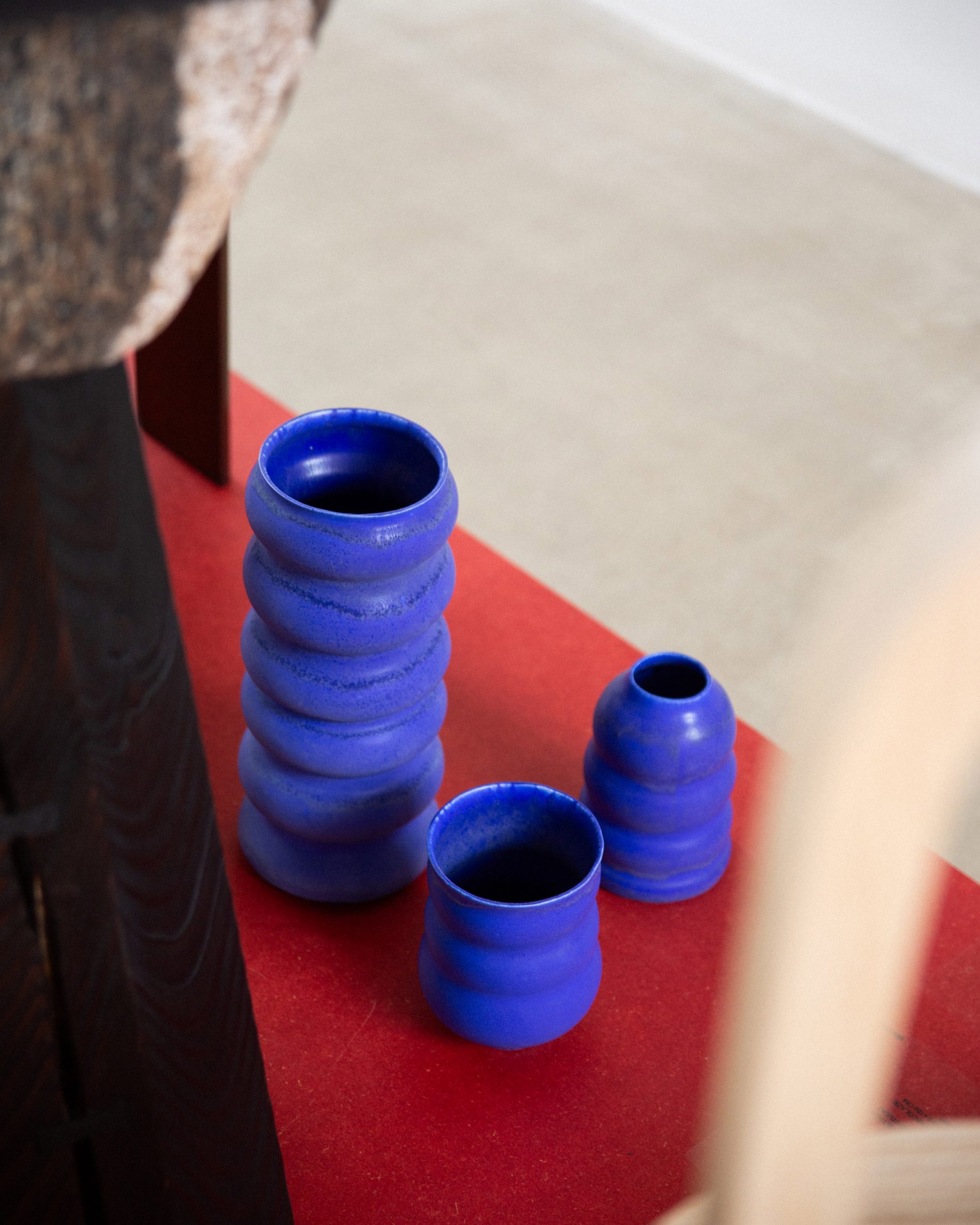 A photograph of three rounded blue vases, atop a red surface.