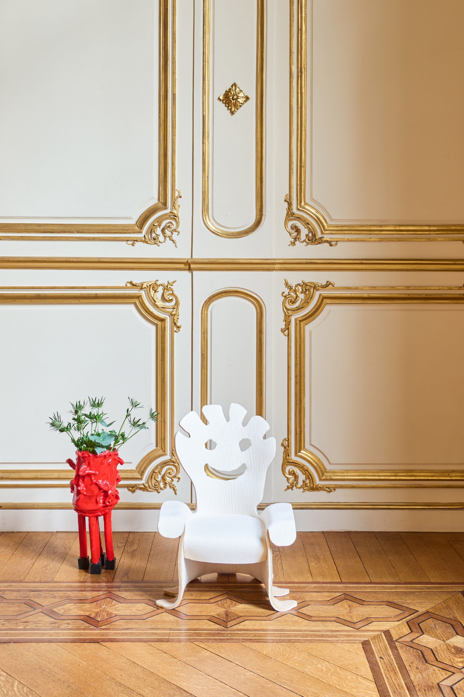 White felt chair next to a red planter